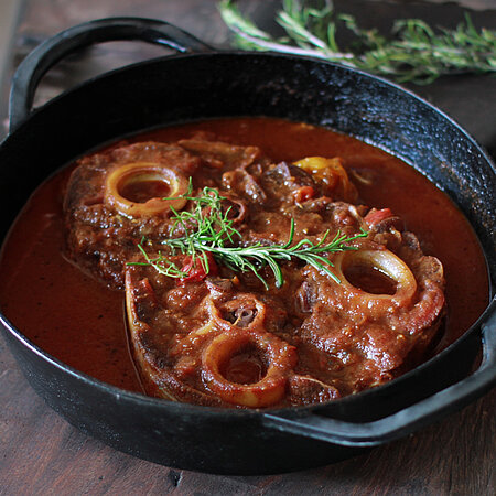 Das Schmorgericht Ossobucco in einer gusseisernen Pfanne. 