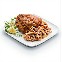 Gegartes Pulled Chicken von WestFood, angerichtet auf einem weißen Teller mit etwas Zitrone.